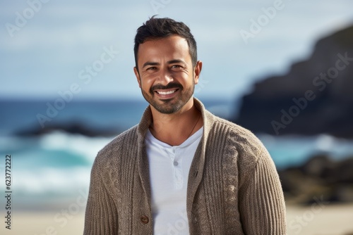 Portrait of handsome man smiling at camera on beach at the day time