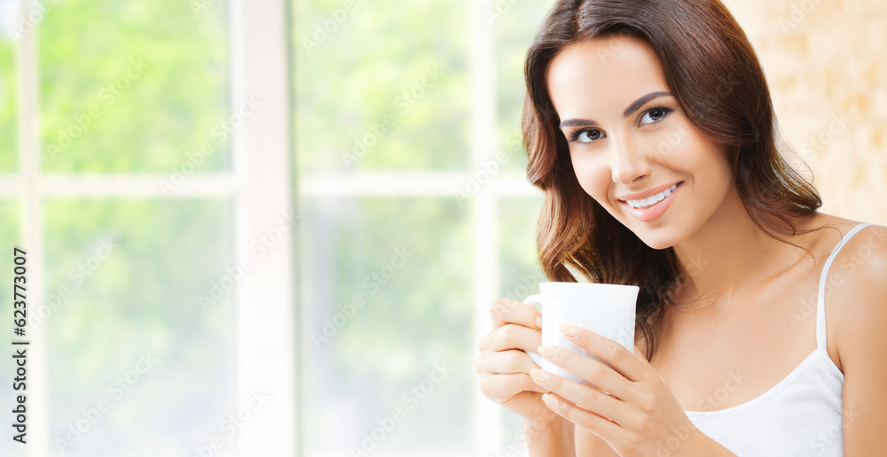 Portrait of happy smiling brunette woman in white lingerie top holding mug cup, drinking coffee or tea, at home, near window and loft style wall. Portrait of happy smiling brunette woman in white lingerie top holding mug cup, drinking coffee or tea, at home, near window and loft style wall.