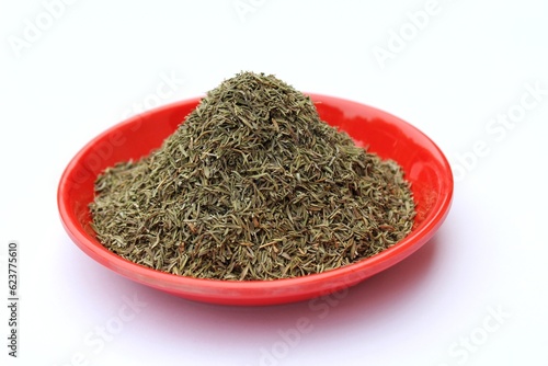 Dried thyme leaves in a plate on white background 