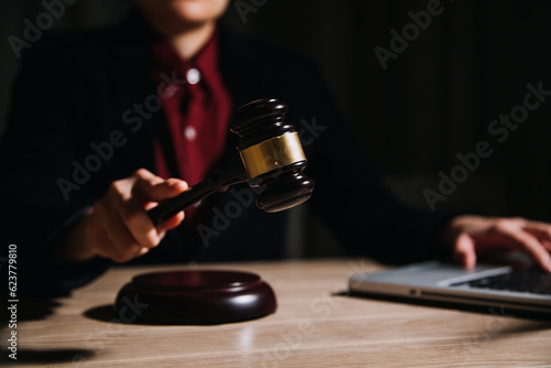 Justice and law concept.Male judge in a courtroom with the gavel, working with, computer and docking keyboard, eyeglasses, on table in morning light