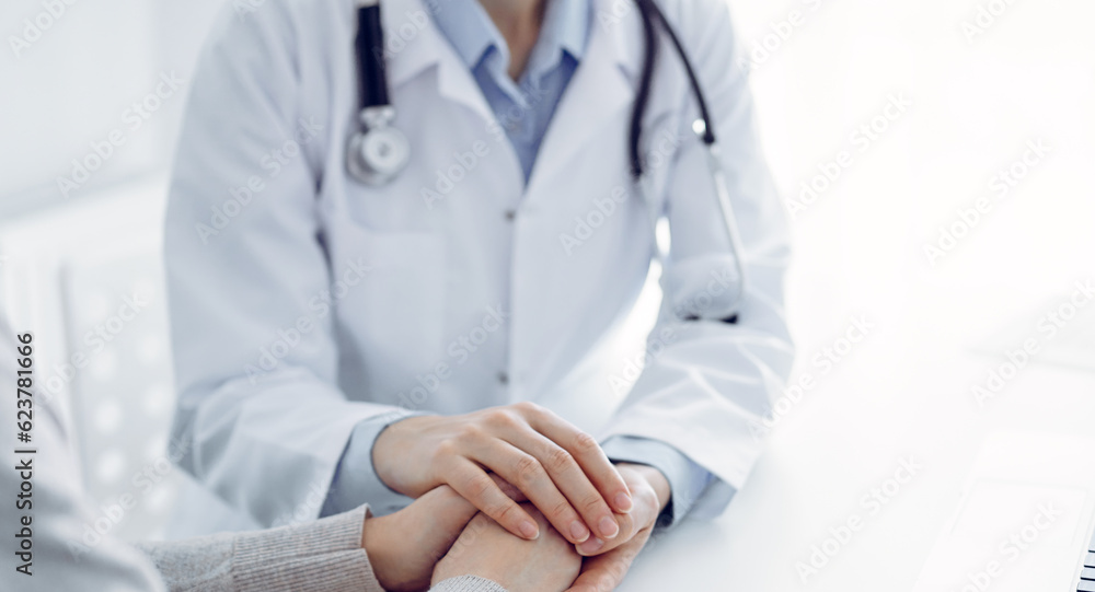 Doctor and patient sitting at the table in clinic office. The focus is on female physician's hands reassuring woman, only hands close up. Medicine concept Doctor and patient sitting at the table in clinic office. The focus is on female physician's hands reassuring woman, only hands close up. Medicine concept