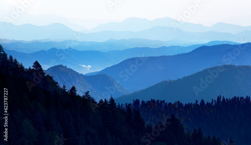 Beautiful landscape with cascade blue mountains at the morning - View of wilderness mountains during foggy weather © muratart