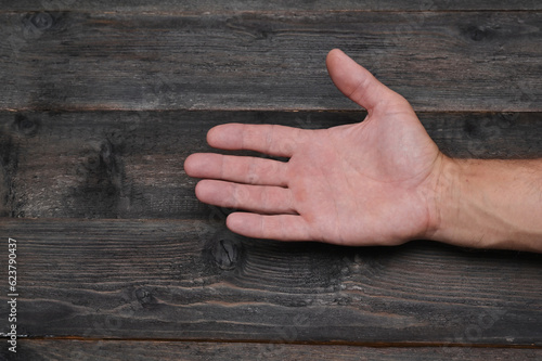 A man's hand on a background of wooden boards. palm close-up.
