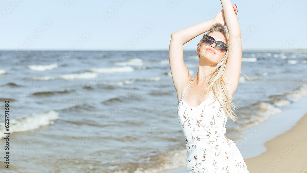 Happy blonde woman in free happiness bliss on ocean beach standing with sun glasses Happy blonde woman in free happiness bliss on ocean beach standing with sun glasses