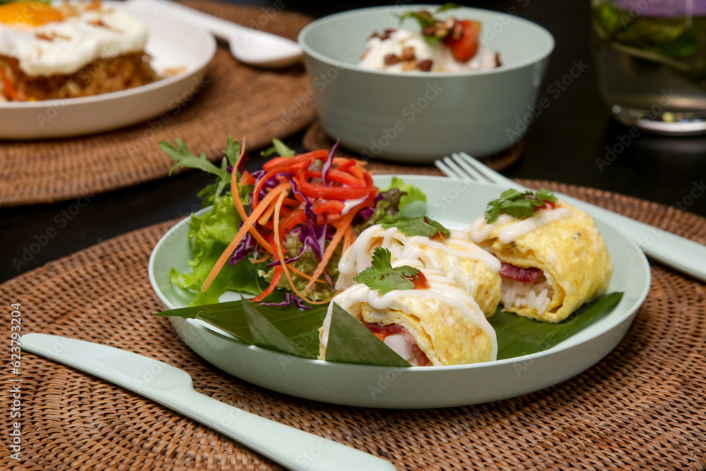 Special egg rolls with rice and salmon served with fresh vegetable salad on the restaurant table Special egg rolls with rice and salmon served with fresh vegetable salad on the restaurant table