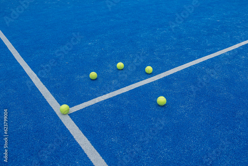 centre line of a blue paddle tennis court with five balls © Vic
