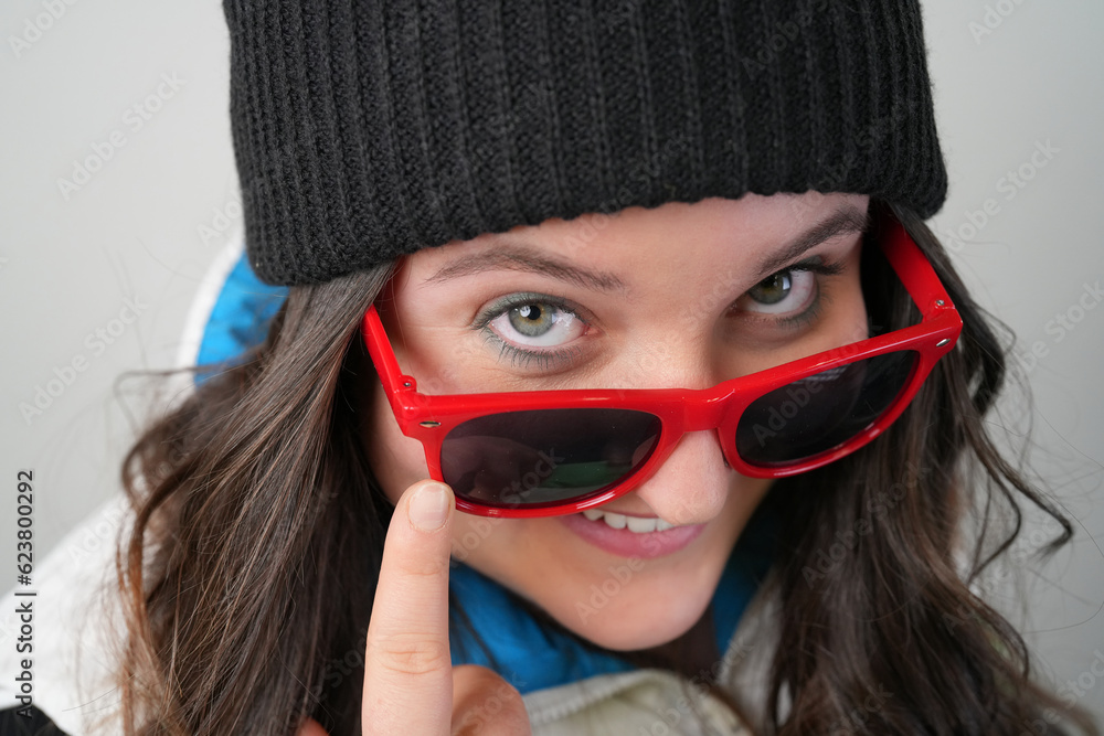 Junge Frau blickt fröhlich über die ränder ihrer roten Sonnenbrille Junge Frau blickt fröhlich über die ränder ihrer roten Sonnenbrille