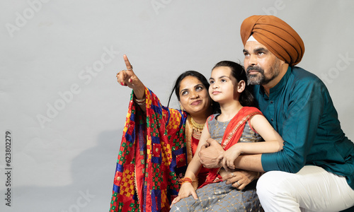 Portrait of Indian sikh Family together pointing towards the right .Lifestyle concept shoot of sikh family with copy space photo