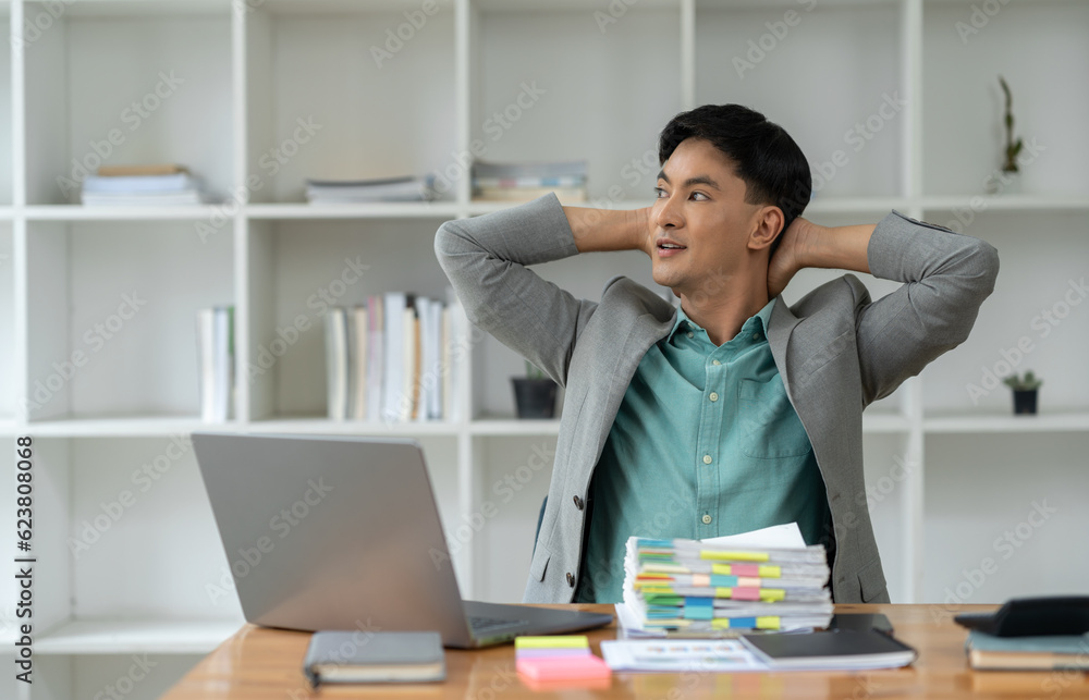 The arm of a young businessman holding his wrist, arm, neck from pain. stretch Relax caused by working for a long time with a laptop computer. Pile of papers, office syndrome, neurological disease. The arm of a young businessman holding his wrist, arm, neck from pain. stretch Relax caused by working for a long time with a laptop computer. Pile of papers, office syndrome, neurological disease.