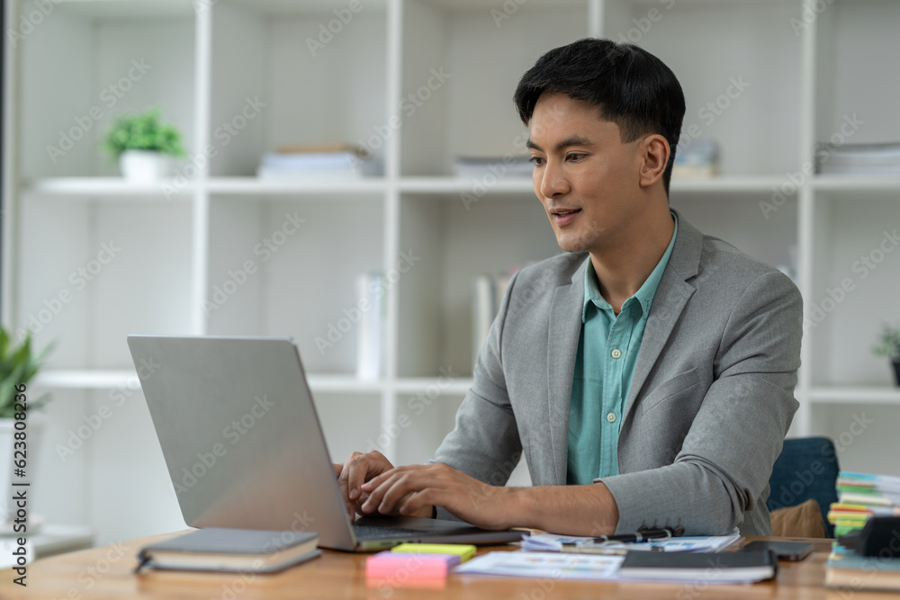 Young Asian businessman working with computer laptop in Analyze plans, search for document information, messaging keyboards, e-commerce, finance technology startup business ideas. Young Asian businessman working with computer laptop in Analyze plans, search for document information, messaging keyboards, e-commerce, finance technology startup business ideas.