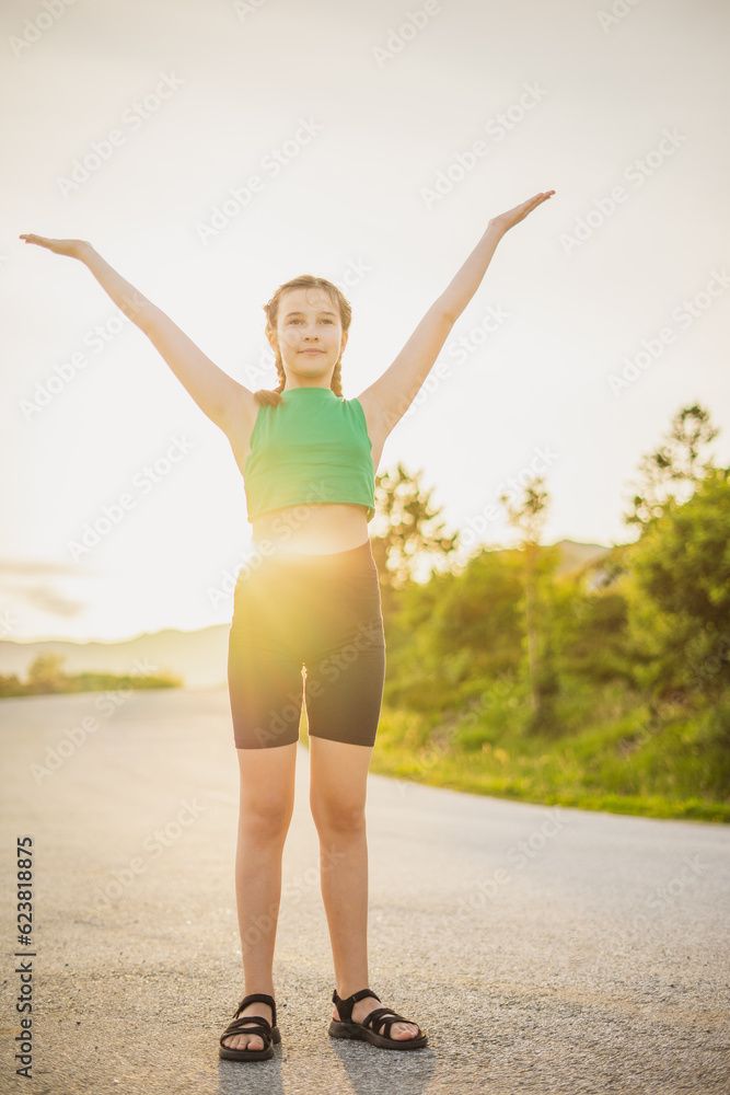 Obraz premium vertical portrait cute girl in tracksuit is engaged in sports activities on road surrounded by nature