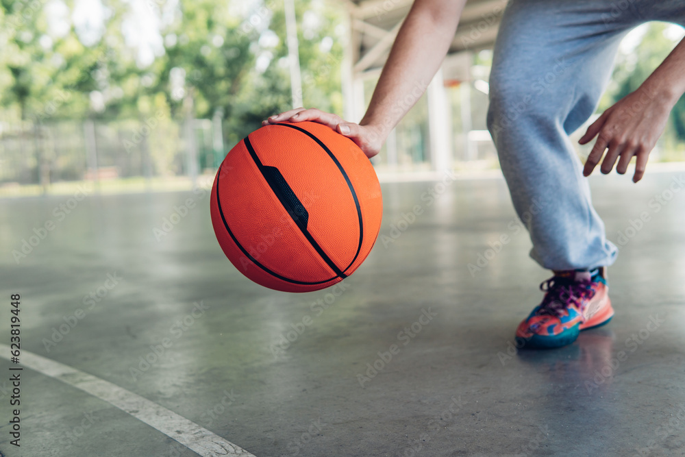 Hand of a boy bouncing a basketball on a court Hand of a boy bouncing a basketball on a court
