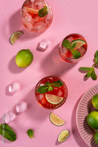 Strawberry mojito. Cocktail with rum  mint  lime and ice in a glass on a pink background. Homemade beverage.