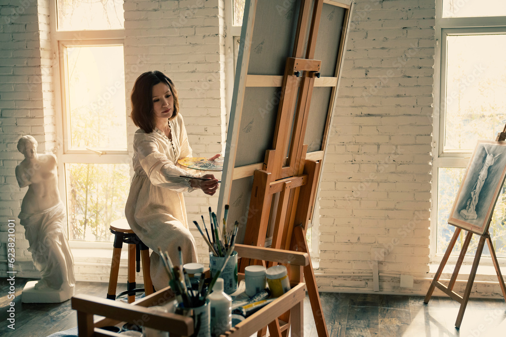 Young female painter painting in a studio Young female painter painting in a studio