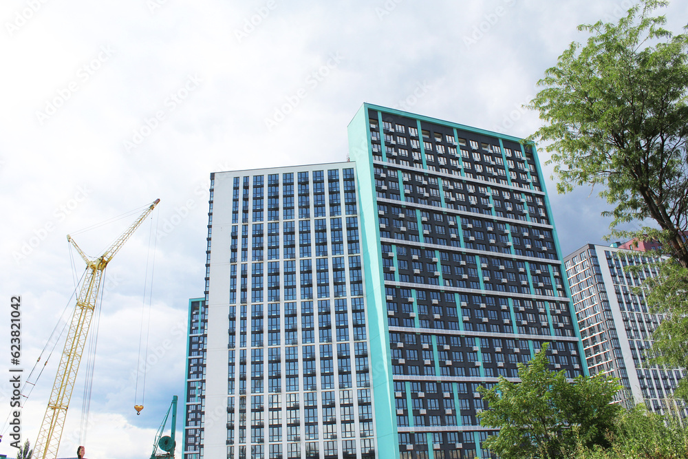 modern office buildings. exterior facades of modern offices and residential apartment buildings in the city of Kyiv, Ukraine with green trees and a crane on a blue sky background
