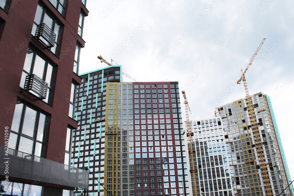building under construction in the city. facade of a new modern building and the construction of a new building with cranes building under construction in the city. facade of a new modern building and the construction of a new building with cranes