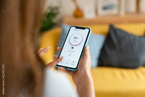 Woman controlling the temperature with a mobile phone.