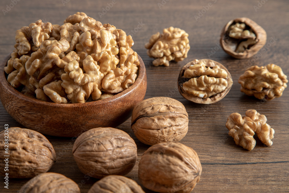 Peeled walnuts and whole walnuts in wooden bowl,top view Peeled walnuts and whole walnuts in wooden bowl,top view