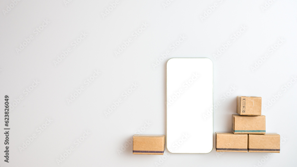 Shopping concept. Cardboard box and phone with blank screen on white background. Online shopping consumers can choose from home shopping and delivery services. with copy space. Shopping concept. Cardboard box and phone with blank screen on white background. Online shopping consumers can choose from home shopping and delivery services. with copy space.