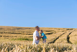 Dad and his little son are having fun walking in a field with ripe wheat. Grain for making bread. the concept of economic crisis and hunger.