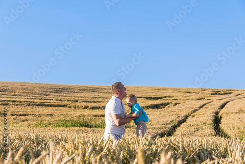 Dad and his little son are having fun walking in a field with ripe wheat. Grain for making bread. the concept of economic crisis and hunger.