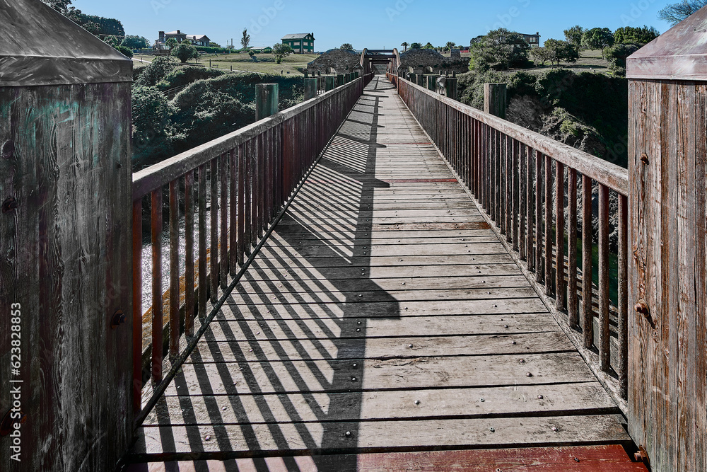 Wooden bridge with arches and brown color, with a viewpoint at the end over the waters of the Ribadeo estuary.