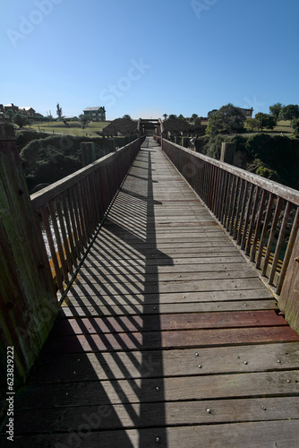 Fototapeta Naklejka Na Ścianę i Meble -  Wooden bridge with arches and brown color, with a viewpoint at the end over the waters of the Ribadeo estuary.