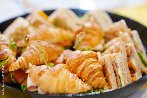 A plate of sandwiches and croissants stuffed with cheese, ham and vegetables.