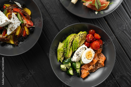 Balanced diet, cooking, culinary and food concept. Ketogenic diet breakfast. Salt salmon salad with avocado, sesame, tomato, cucumber and quail egg. Copy space