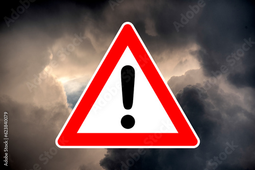Piktrogramm eines Warndreiecks mit Ausrufezeichen vor dramatischem Unterwetterhimmel als Symbol für Unwetterwarnung