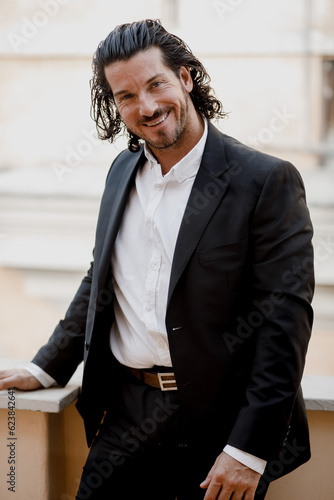 A handsome brunette Spaniard in a classic suit walks through the city