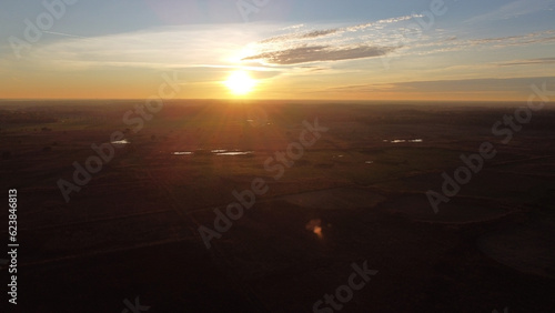 Aerial drone view of African looking nature landscape with a field  a forest and small lakes captured during sunset golden hour.