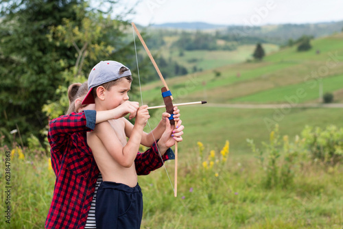 A little boy wants to grow up strong and brave, he learns to shoot a wooden bow in nature, his older sister helps him, boy learns to be a man and protect his family