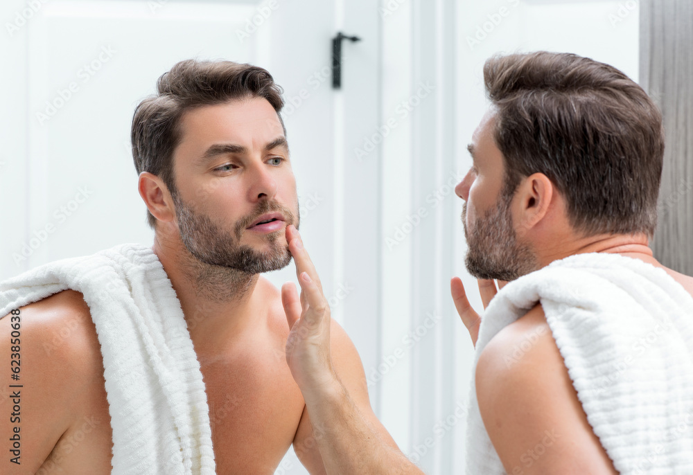 Close-up portrait of perfect brunet man touching chin and skin. Handsome man touching face in front of the mirror in bath. Perfect skin. Man cosmetic, skin treatment. Hygiene and skin care male face. Close-up portrait of perfect brunet man touching chin and skin. Handsome man touching face in front of the mirror in bath. Perfect skin. Man cosmetic, skin treatment. Hygiene and skin care male face.