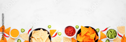 Nachos and dip bottom border. Top view on a white marble banner background. Copy space.