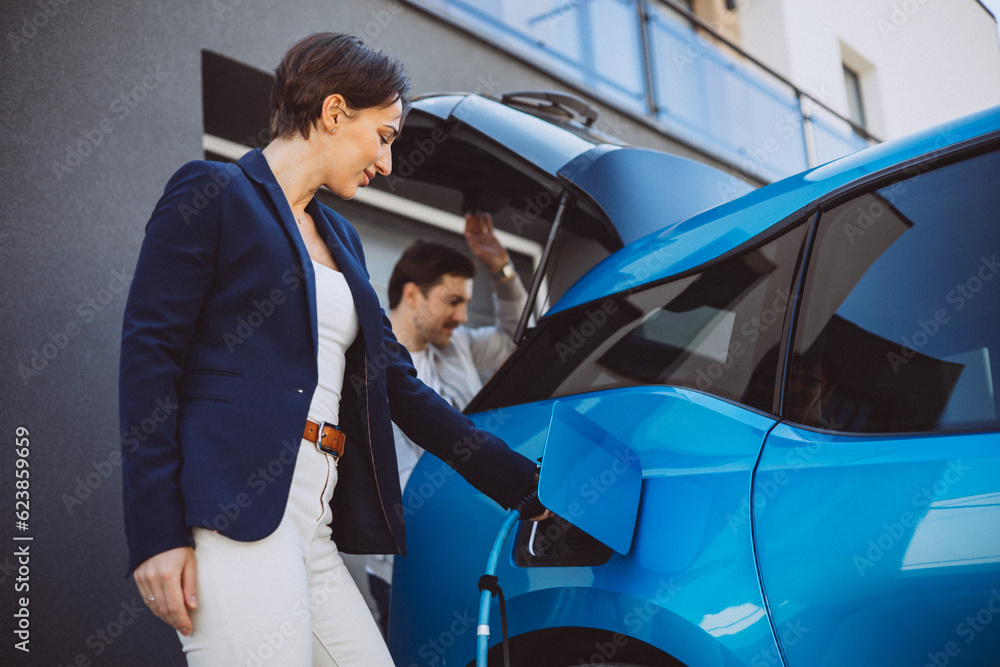 Couple talking by their electric car while its charging Couple talking by their electric car while its charging