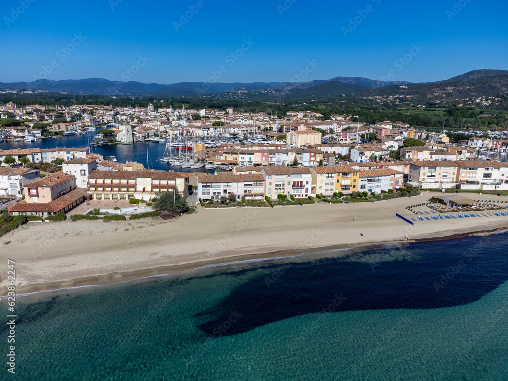 Arial view on blue water of Gulf of Saint-Tropez, sandy beach, houses in Port Grimaud, village on Mediterranean sea with yacht harbour, Provence, summer vacation in France