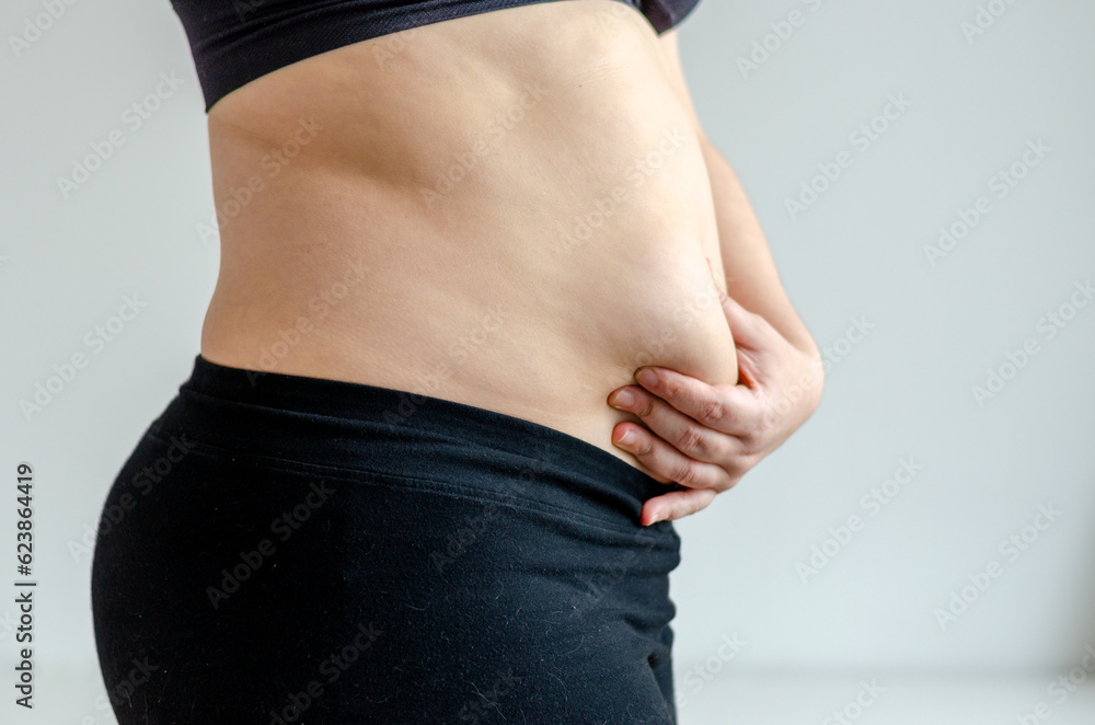 Naklejka premium Overweighted woman squeezing belly seen from side