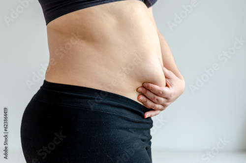 Overweighted woman squeezing belly seen from side