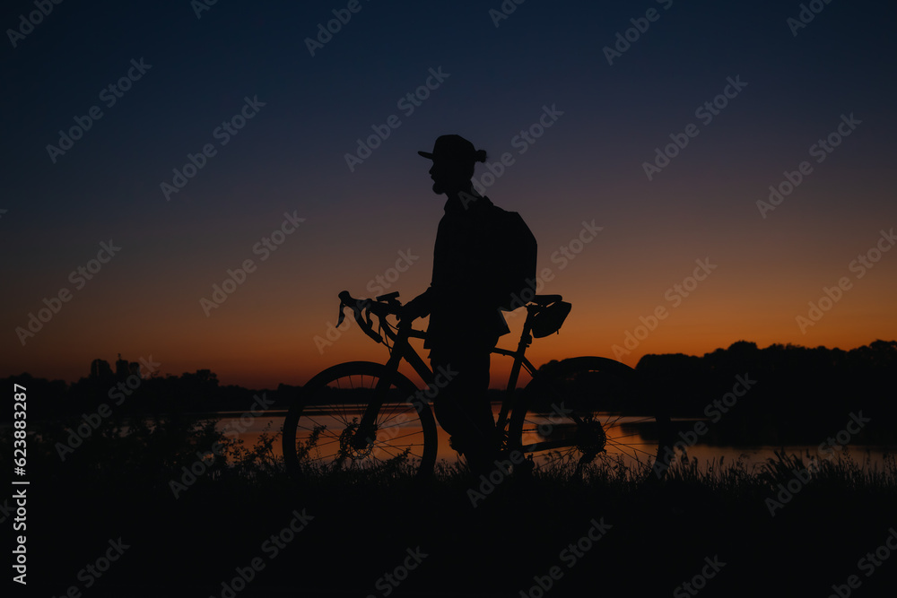 Silhouette of a man with a bicycle enjoying the sunset.