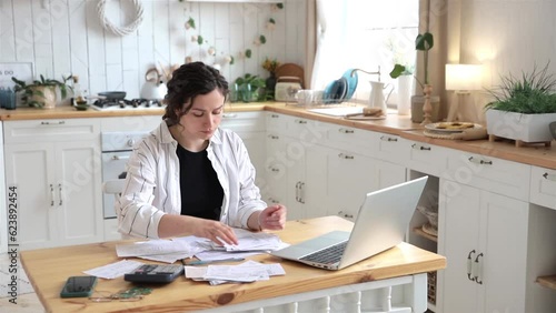 Stressed sad woman with financial problems can't handle emotions dealing with taxes and threw all receipt from the desktop. She has no money to pay utility bills or loan. Debt or bankruptcy concept