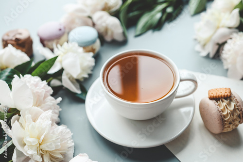 Cup of tea, macaroons and peonies, flat lay top view. good morning concept