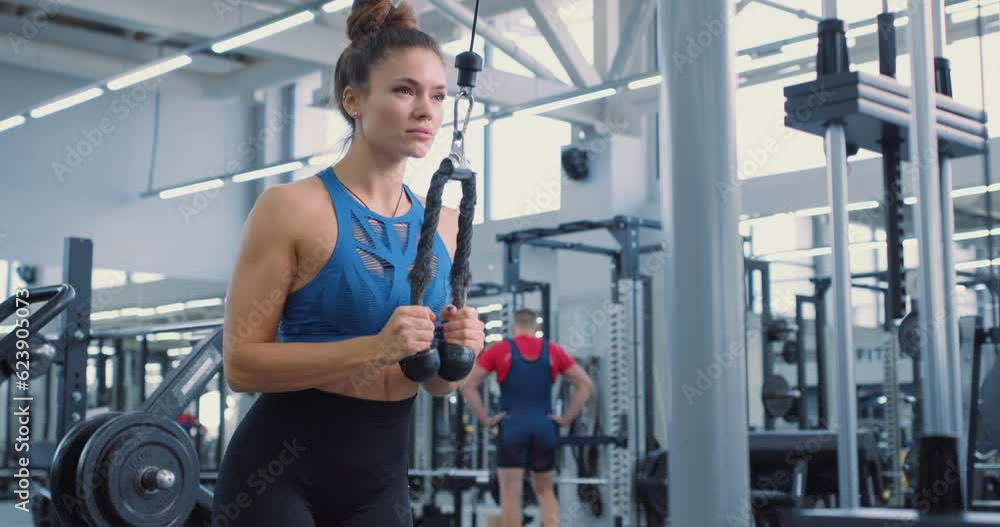 motivated fitenss woman pulling exercise equipment in gym slow motion, lifestyle, hobby, interests, sportswoamn performs the triceps pushdown. Arms exercises. Motivation, challenge motivated fitenss woman pulling exercise equipment in gym slow motion, lifestyle, hobby, interests, sportswoamn performs the triceps pushdown. Arms exercises. Motivation, challenge