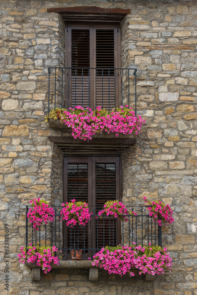Old stone house with beautiful flowers at the window in the medieval village of Ainsa in the pyrenees, Aragon, Spain