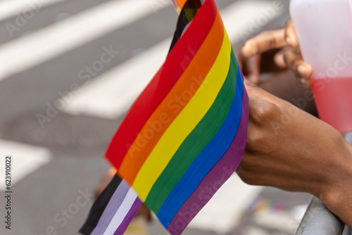 A hand hold a colorful gay pride LGBT rainbow flag