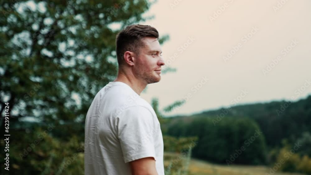 Confident mid-aged Caucasian man wearing white shirt. Smiling muscular man folds hands on the chest looks at camera. Blurred nature backdrop. Confident mid-aged Caucasian man wearing white shirt. Smiling muscular man folds hands on the chest looks at camera. Blurred nature backdrop.