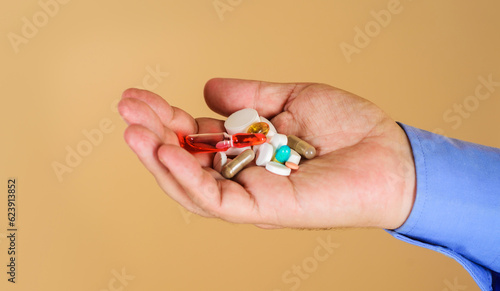 Man hand with different pills, capsules and ampoule. Immune system vitamins and supplemets. Man with pills in hand. Treatments and healthcare. Handful of variety medicine pills prescribed by doctor. photo