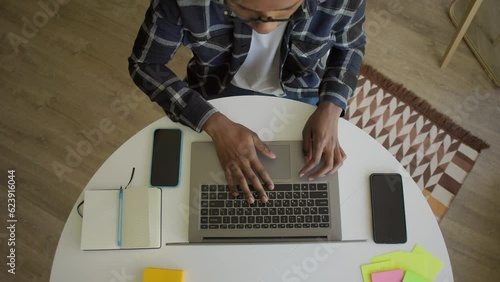 African-American freelance working from home at her desk opens laptop computer top view overhead shot, zoom out of businessman opening notebook and start typing
