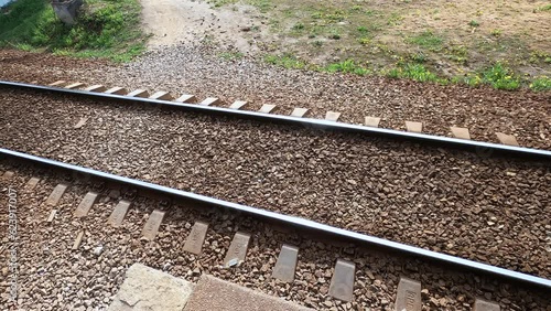The railway track is seen with steel rails and railroad infrastructure. The travel through urban outdoor way. Gravel and metal tracks. Iron direction of transport industry.