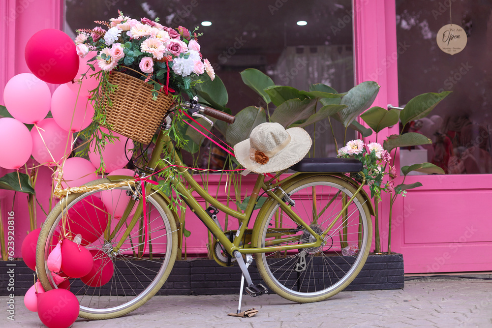 Terrace of pink French-style cafe with a bicycle with a basket of pink flowers and balloon. Decor facade of coffeehouse with classic bike. 